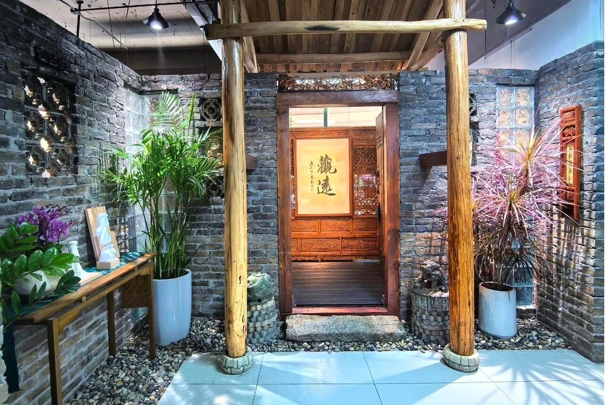 The entrance to FuBlessings calligraphy studio — wooden columns, a grey-brick wall, and a hanging scroll reading 觀遠 (gaze far)