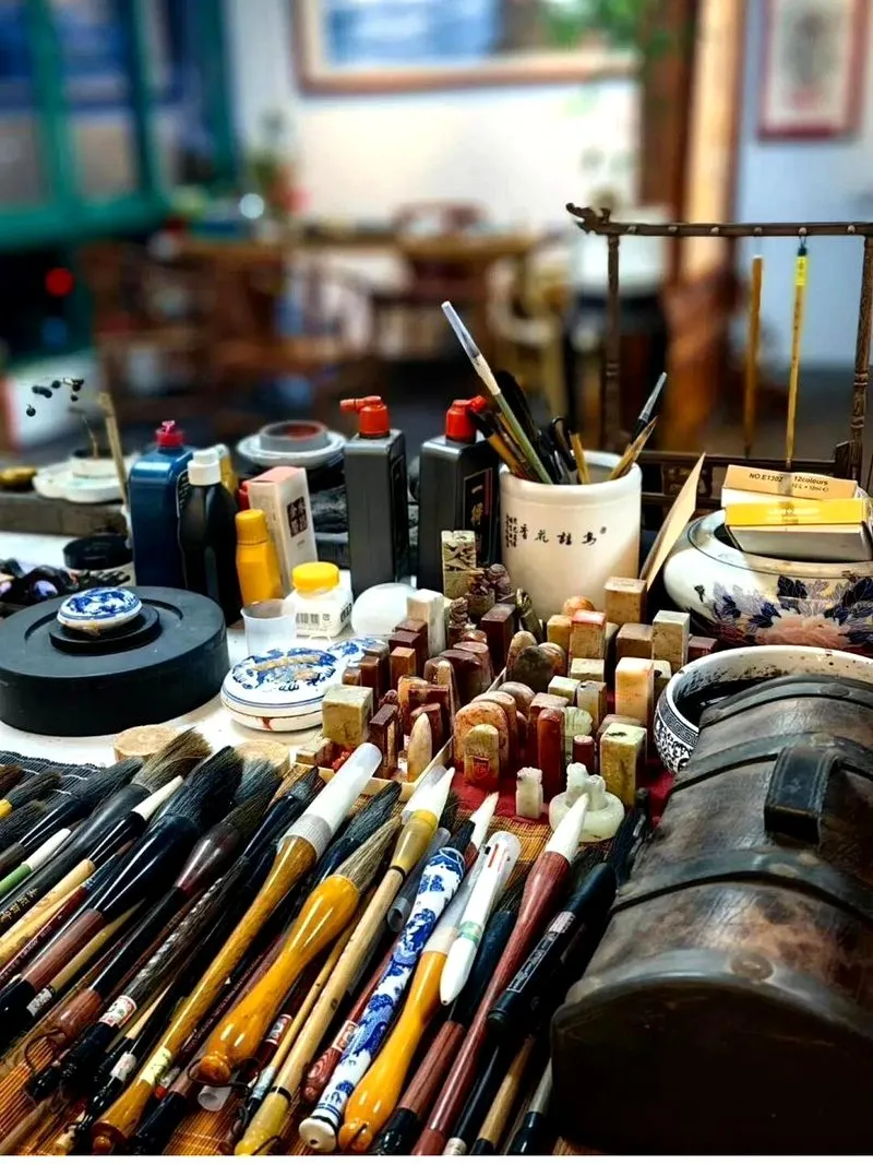 The studio workbench — a row of brushes of different sizes and materials, alongside ink stones, seal stones, and porcelain tools